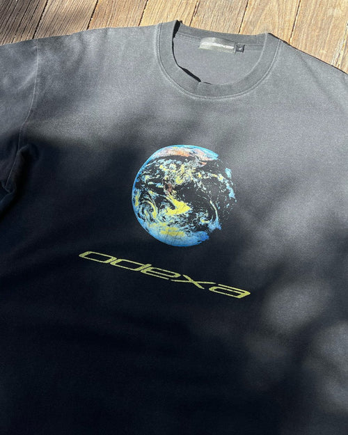 Washed black vintage tee with earth graphic and yellow ODEXA text, flat lay