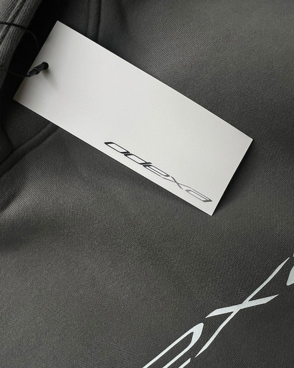 Close-up of grey hoodie with white ODEXA logo and hang tag