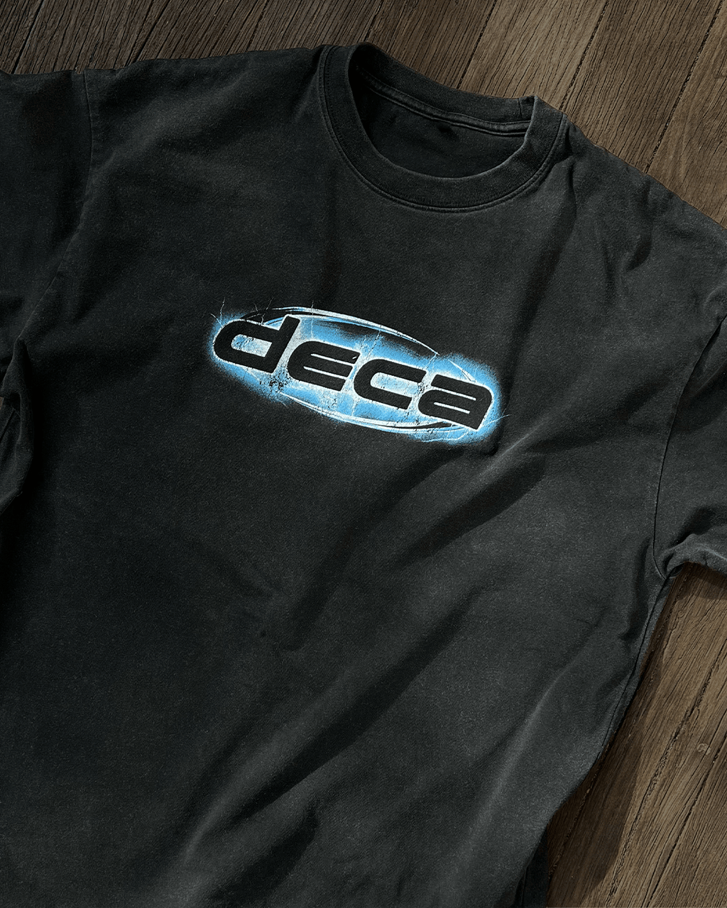 Washed black vintage tee with blue chrome DECA logo print, flat lay