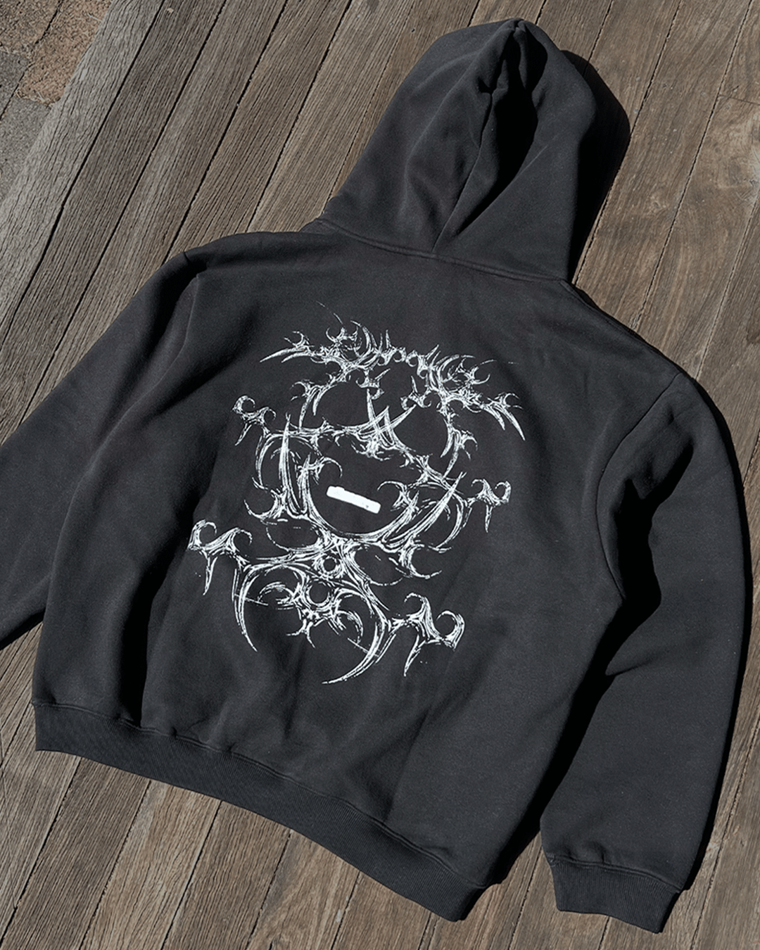 Black boxy hoodie with white tribal bone back print, flat lay