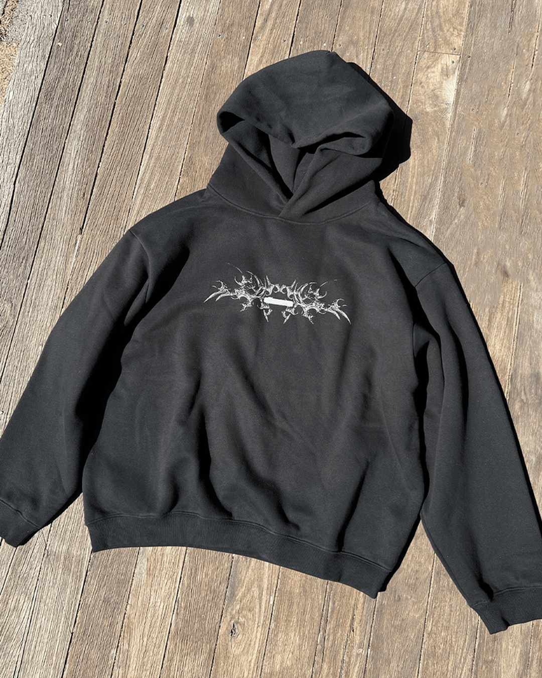 Black boxy hoodie with white bone chest print, front flat lay