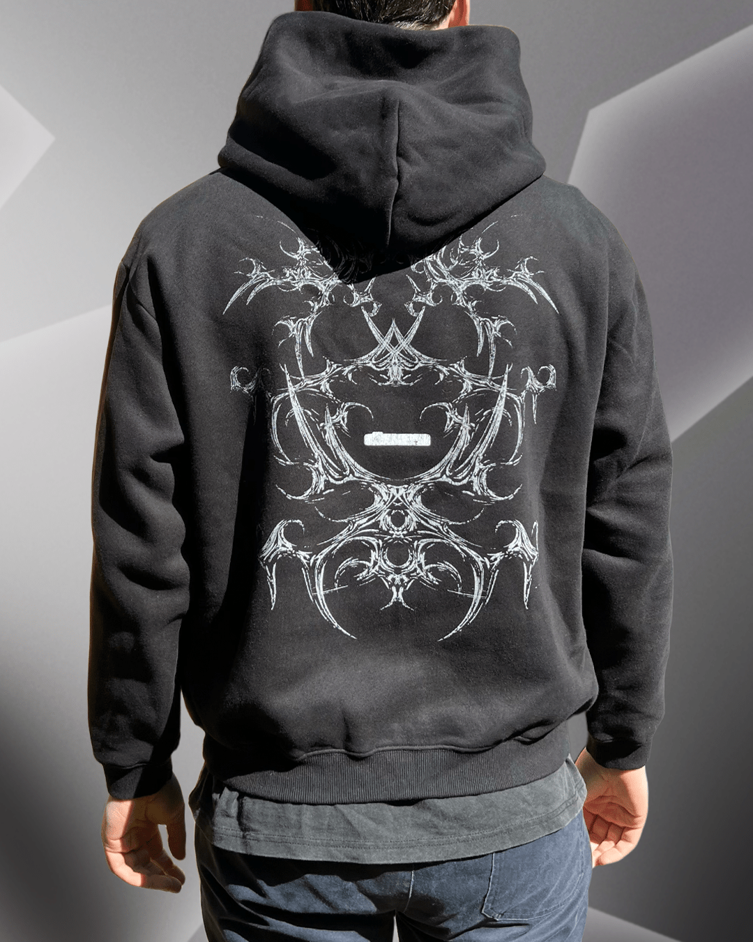 Model wearing black White Bone boxy hoodie, back view with tribal bone print