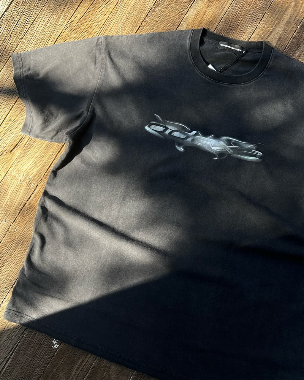Washed black vintage tee with chrome ODEXA logo, sunlit flat lay