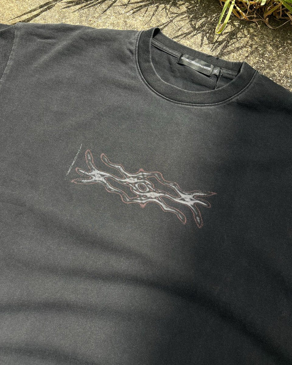 Washed black vintage tee with red and white digital decay tribal print, flat lay