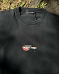 Washed black vintage tee with small red droplet text chest print, flat lay