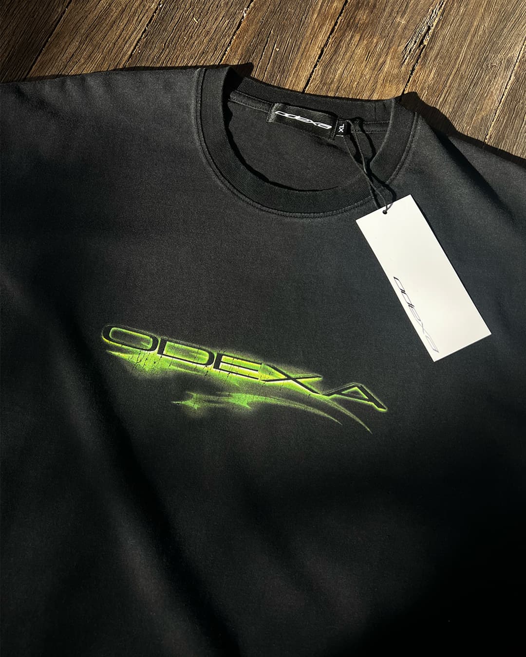 Washed black vintage tee with neon green ODEXA logo, flat lay
