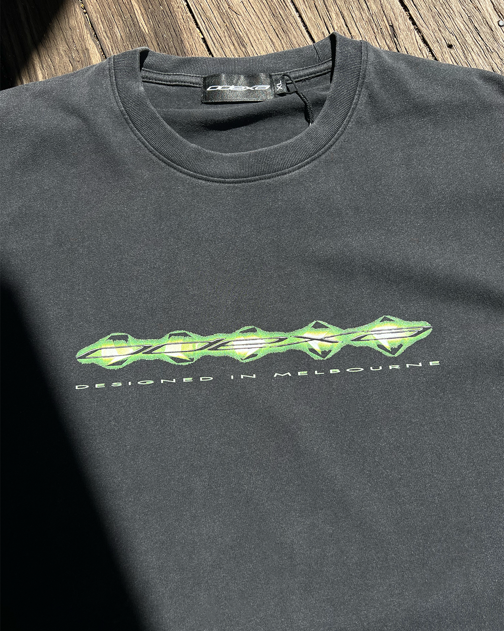Washed black vintage tee with green digital ODEXA logo print, front view