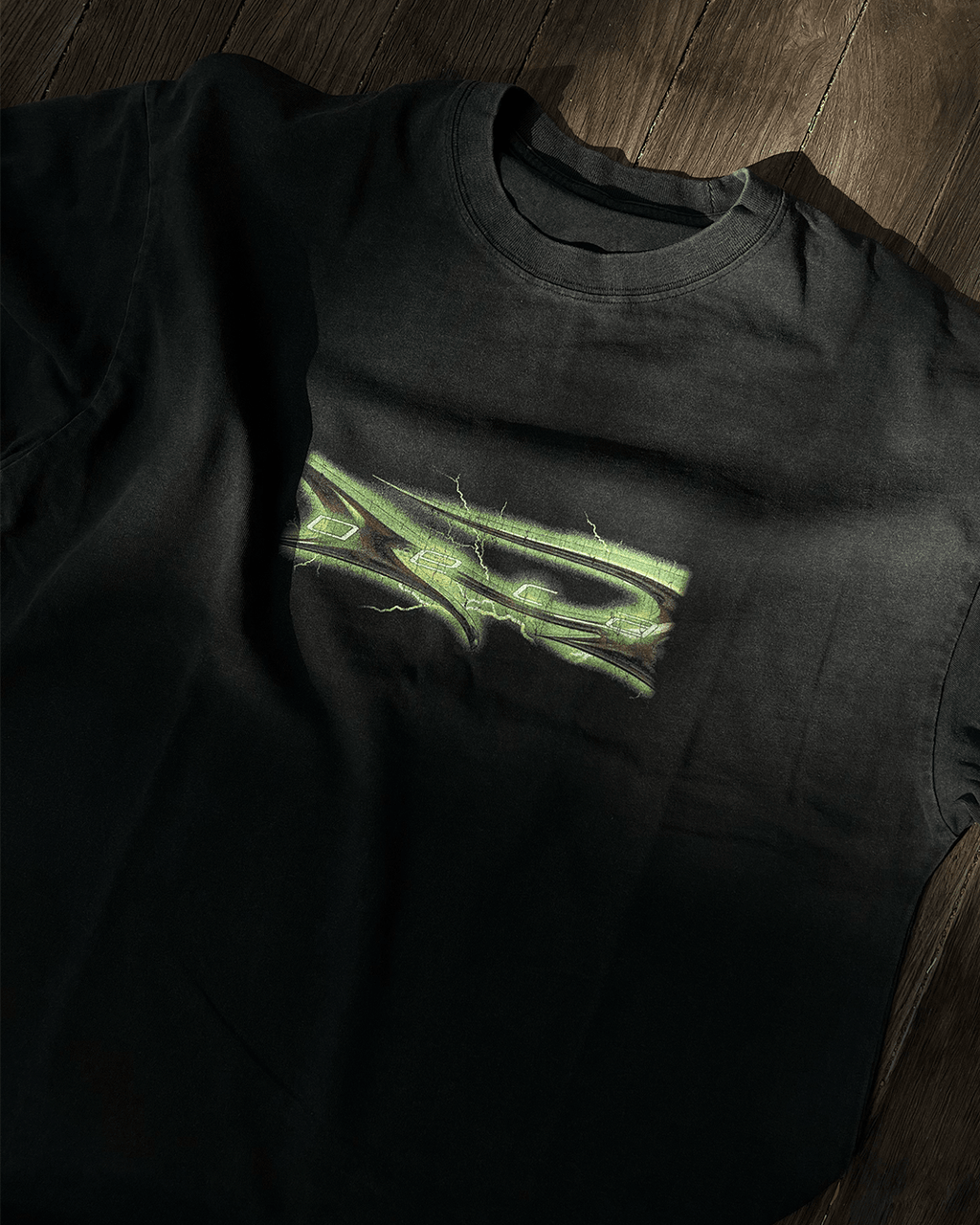 Washed black vintage tee with green glow tribal logo print, flat lay
