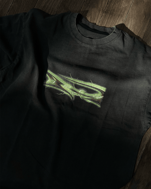 Washed black vintage tee with green glow tribal logo print, flat lay