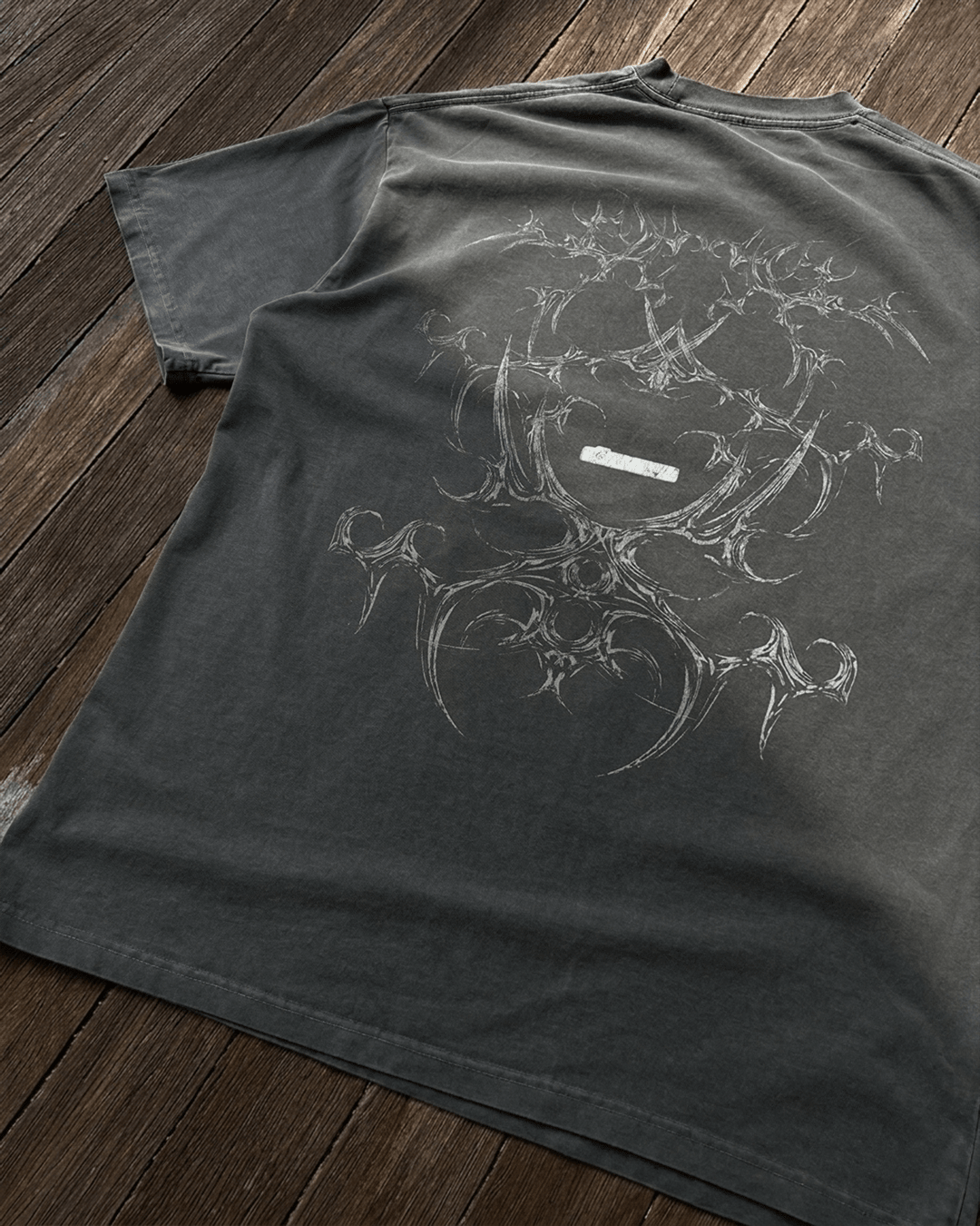 Faded grey vintage tee with tribal bone line art print, flat lay
