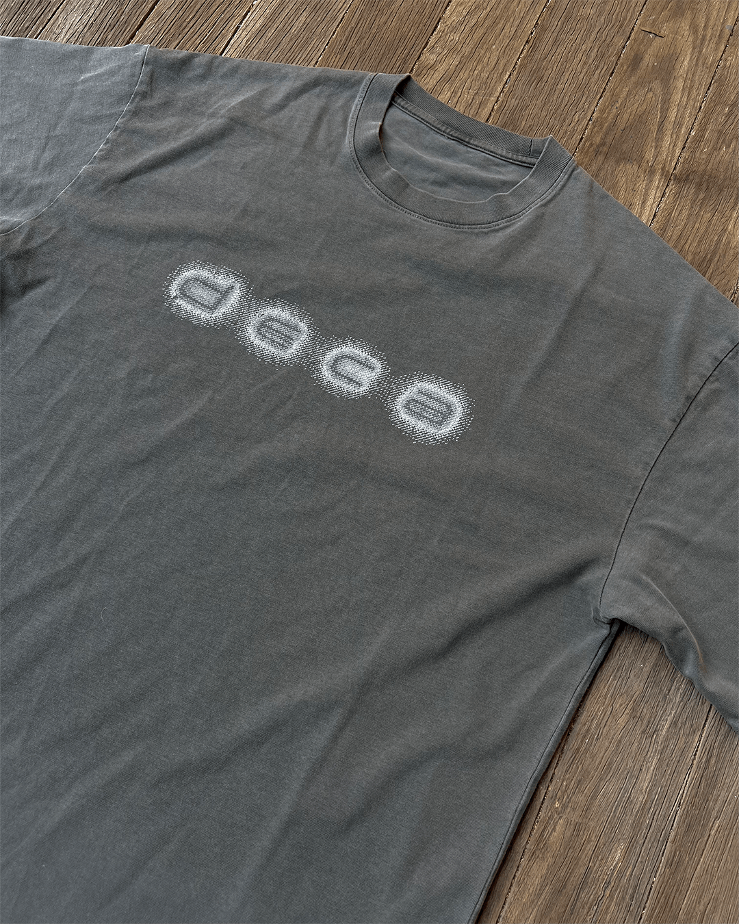 Grey vintage tee with blurred white DECA logo print, flat lay