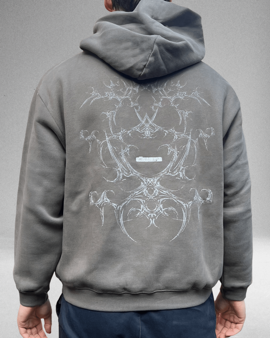 Model wearing moss grey White Bone hoodie, back view showing tribal bone print