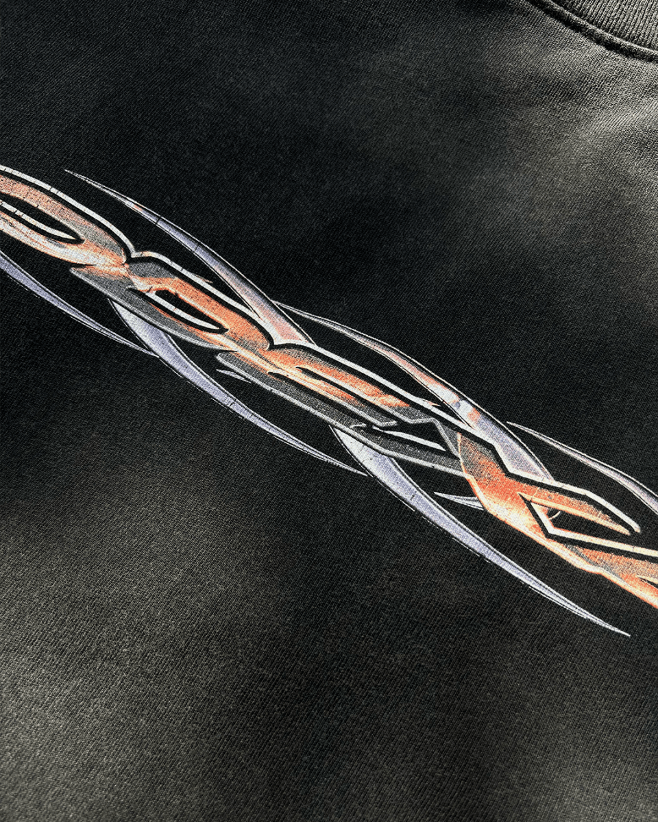 Close-up of orange chrome tribal logo print on black tee