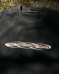 Washed black vintage tee with orange chrome tribal logo, flat lay