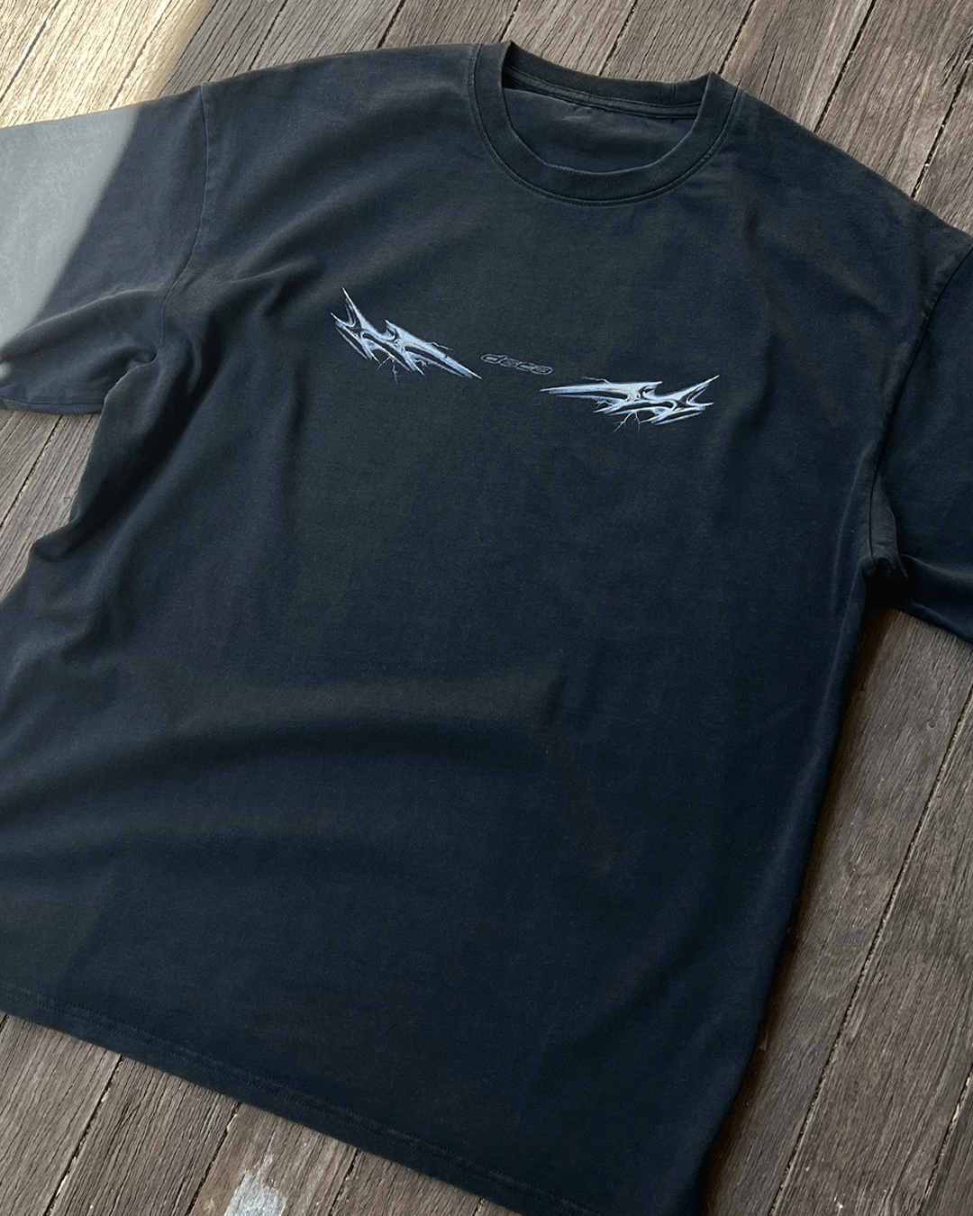 Washed black Lightning Chrome vintage tee on wooden boards, flat lay