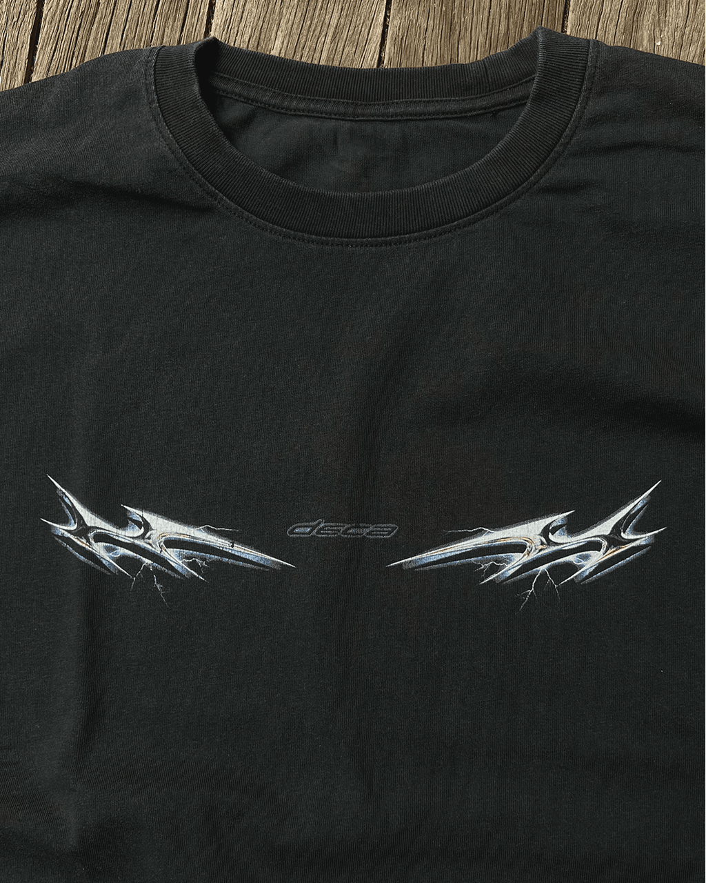 Black vintage tee with chrome lightning tribal print, flat lay