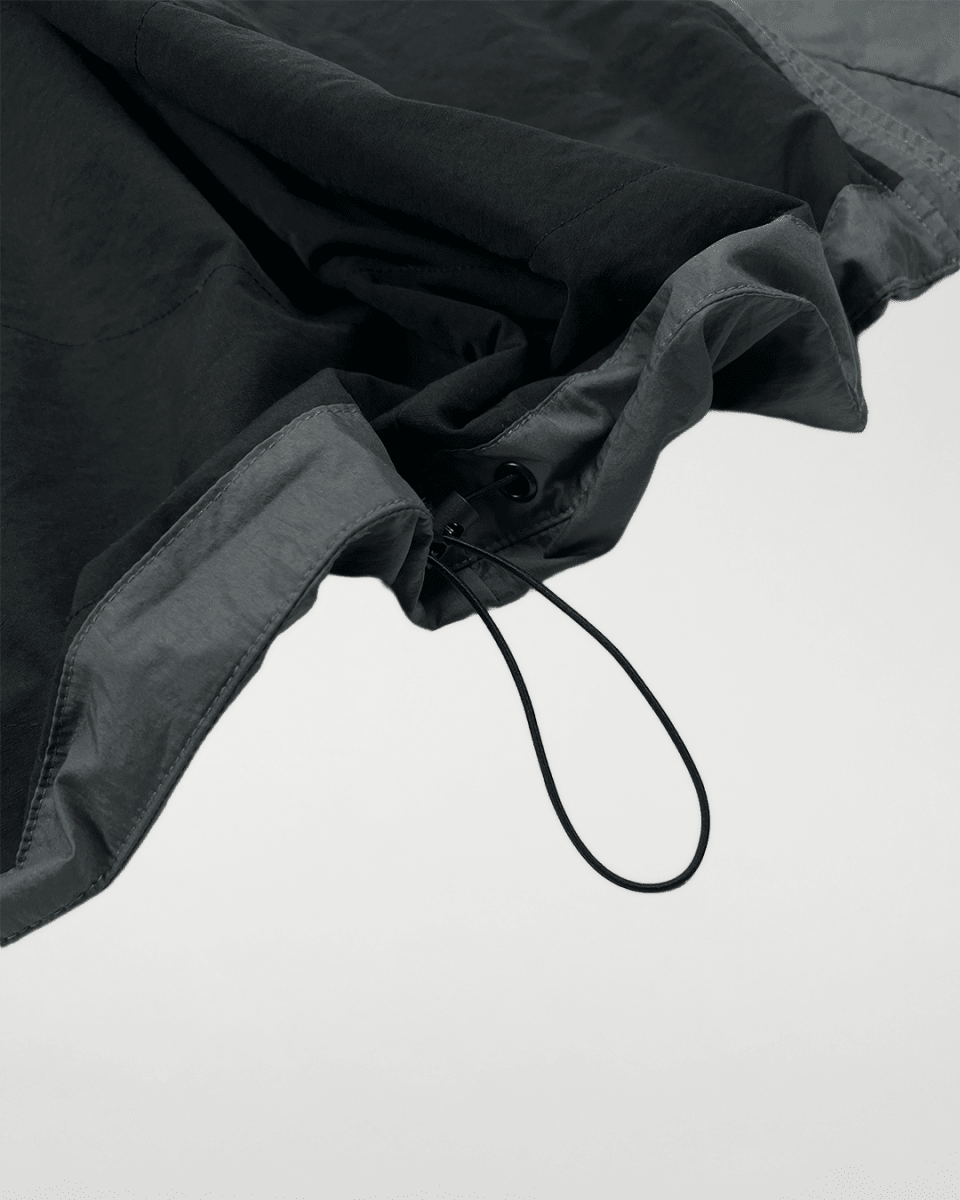 Close-up of slate green windbreaker drawcord hem
