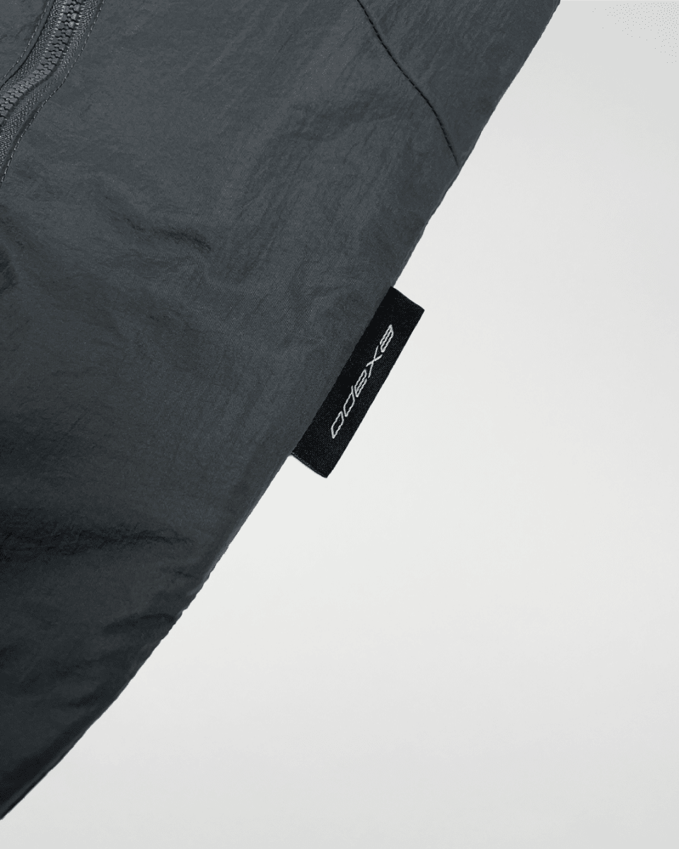Close-up of slate green windbreaker hem with ODEXA label