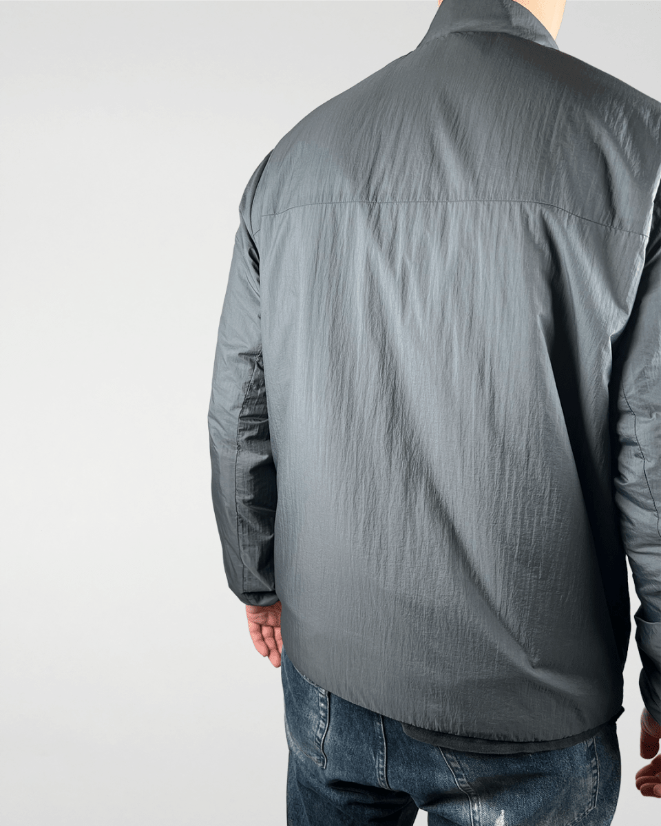 Model wearing slate green windbreaker jacket, back view