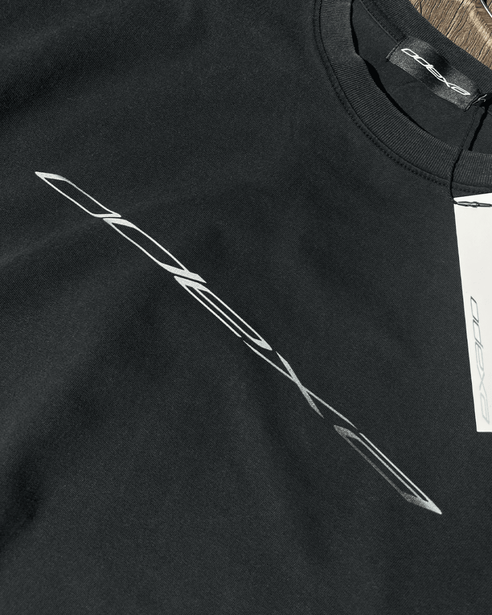Close-up of diagonal chrome logo print on black vintage tee