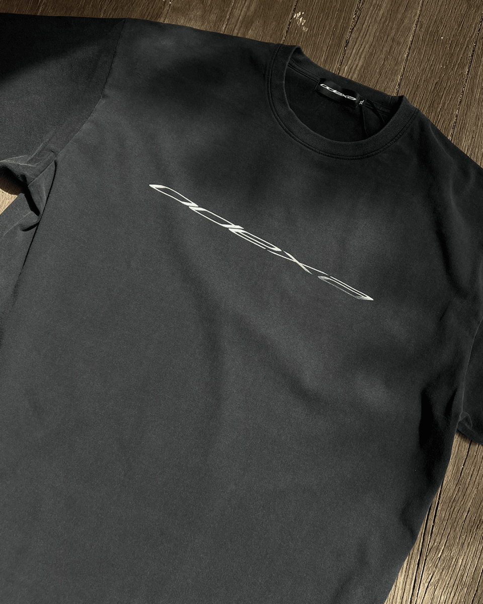 Washed black vintage tee with diagonal chrome logo print, flat lay