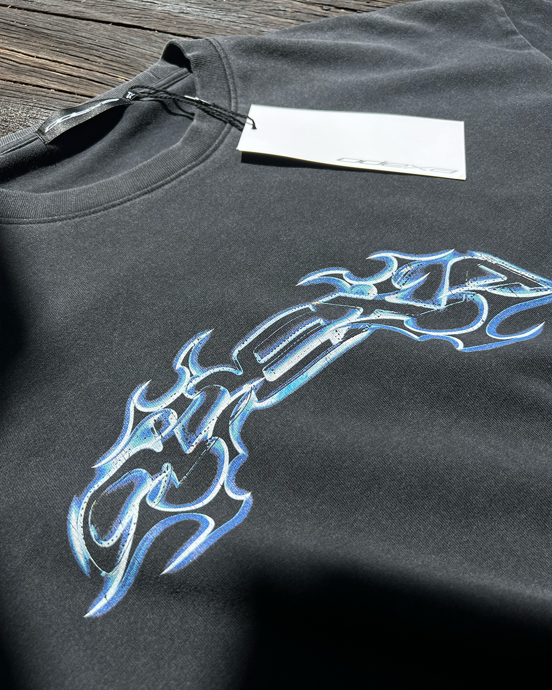 Washed black Neon Text vintage tee with blue chrome tribal print, angled view