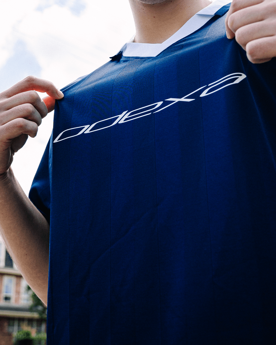 Person holding up navy ODEXA 1 jersey showing chest logo
