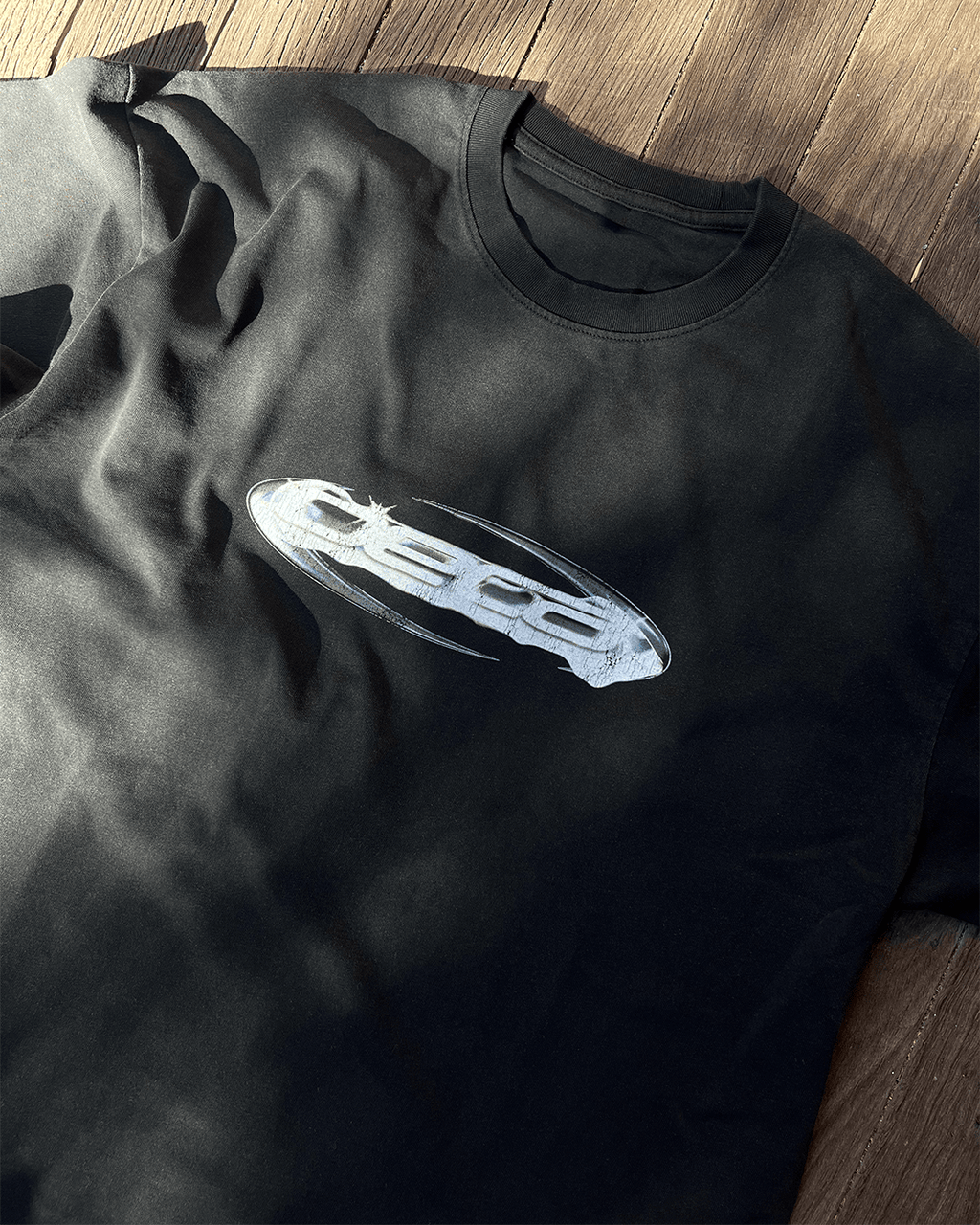Close-up of chrome Opal logo print on washed black vintage tee