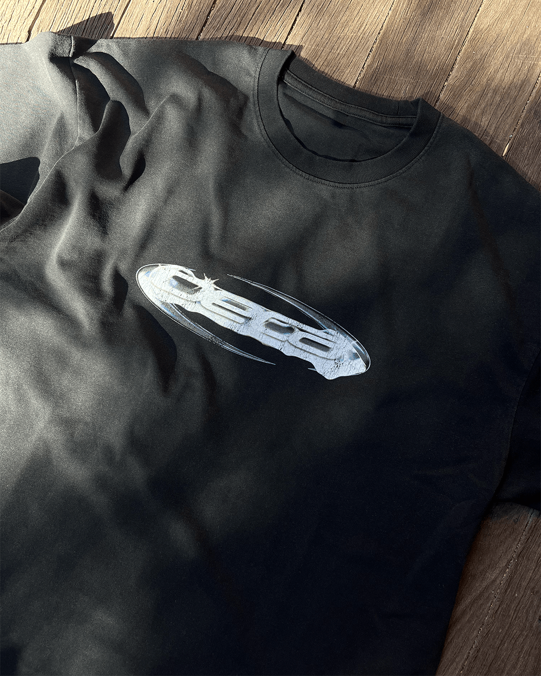 Close-up of chrome Opal logo print on washed black vintage tee