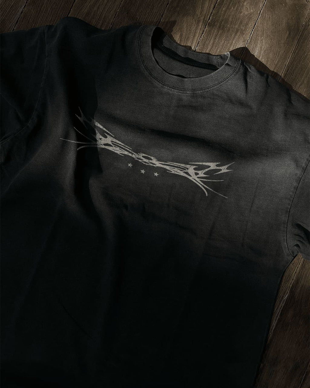 Washed black vintage tee with chrome tribal sigil and stars print, flat lay