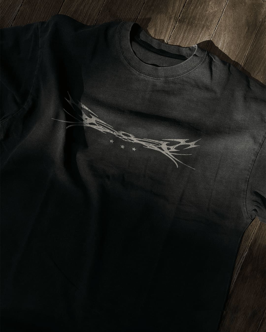 Washed black vintage tee with chrome tribal sigil and stars print, flat lay