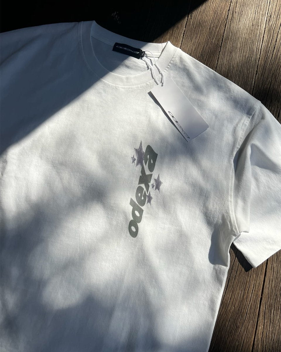 White vintage tee with vertical ODEXA chest logo, sunlit flat lay