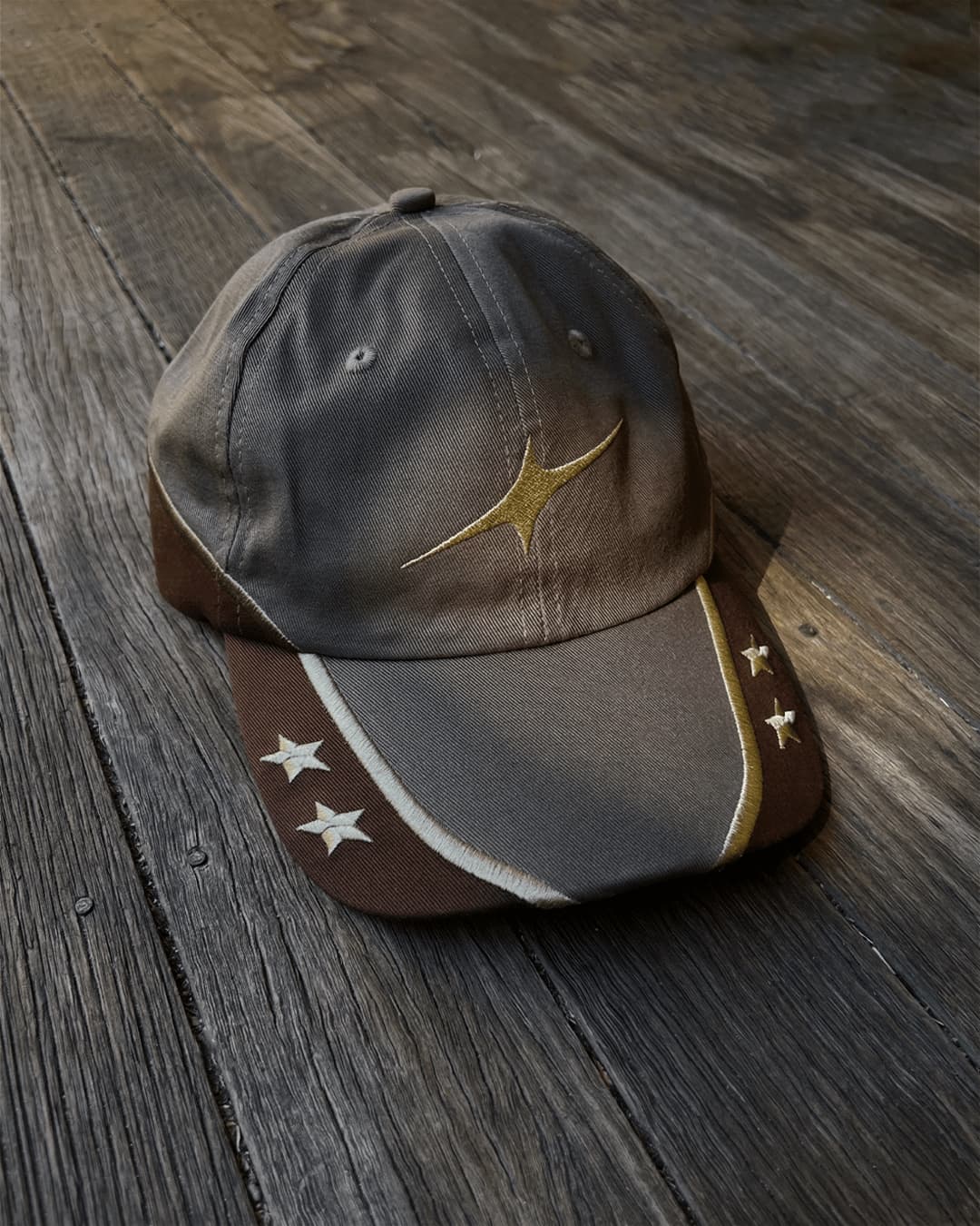 Brown and grey contrast cap with gold star and white stars, on wooden floor