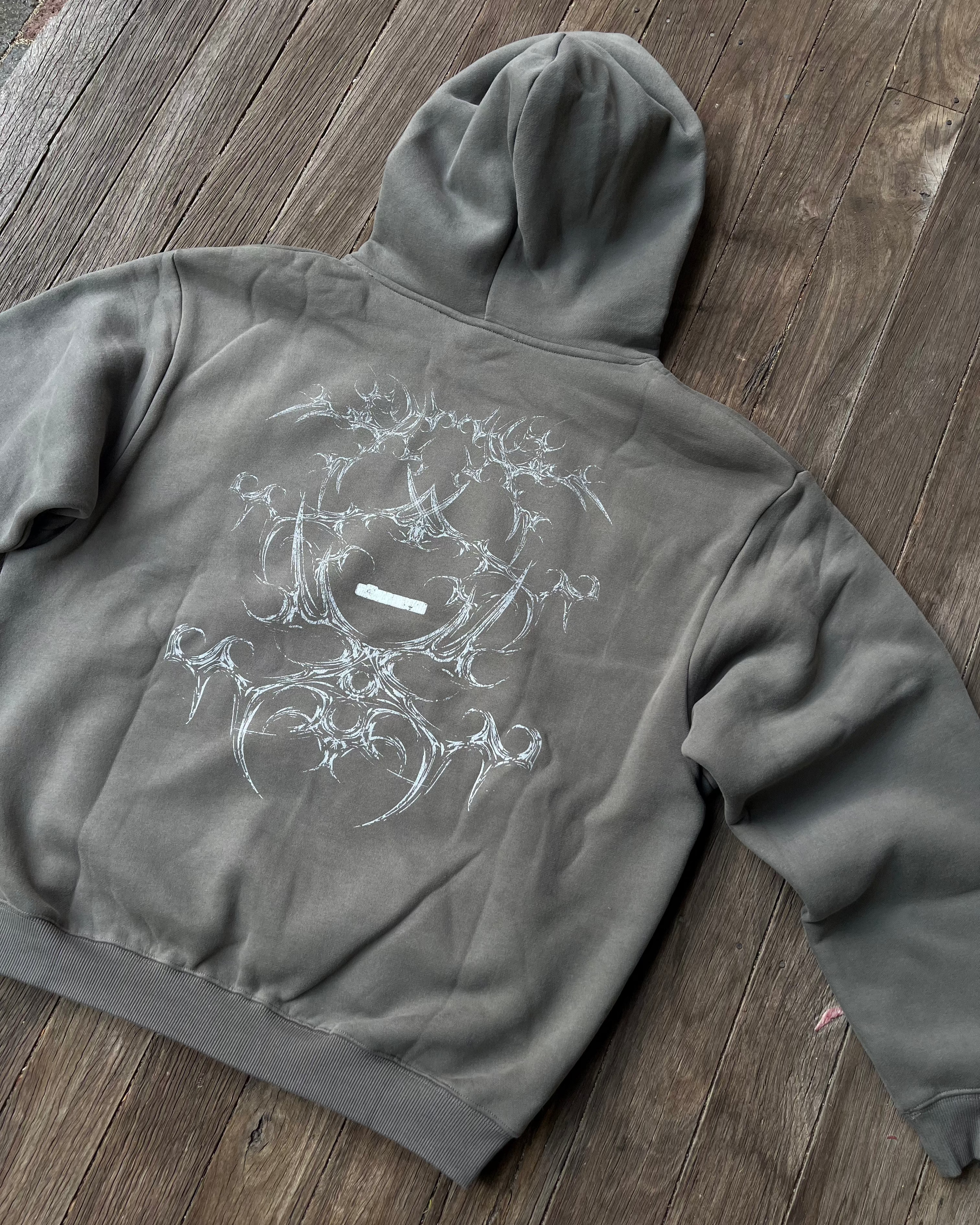 Moss grey boxy hoodie with white tribal bone back print, flat lay
