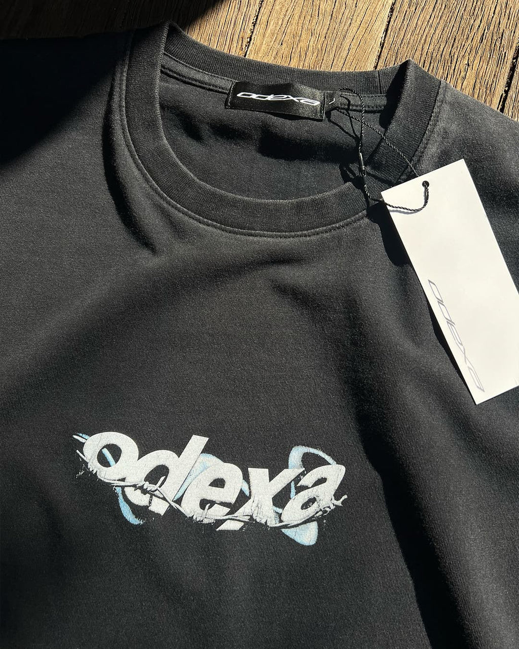 Washed black vintage tee with white wire ODEXA logo, flat lay